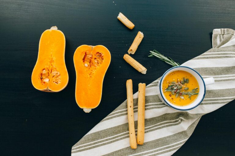 A flat lay of butternut squash soup with scattered ingredients on a table.